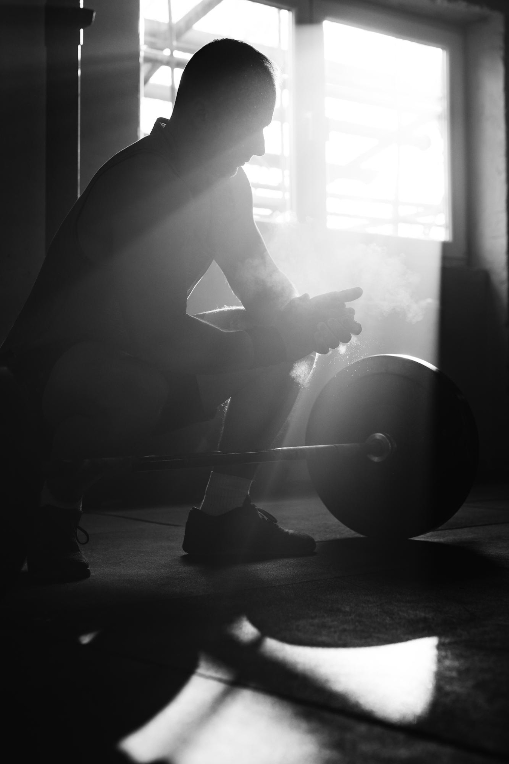Black and white athlete resting beside a loaded barbell